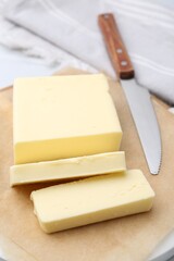 Cut block of fresh butter and knife on white table, closeup