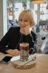 Smiling senior woman enjoying tea in cozy cafe