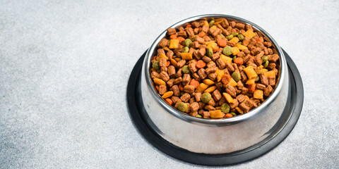 Pet bowl with dry food on a gray textured background. Studio photo.