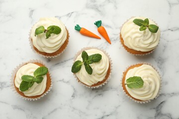 Delicious carrot cupcakes with mint on white marble table, flat lay
