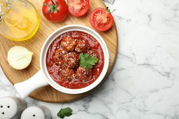 Delicious meatballs with tomato sauce, parmesan cheese and parsley served on white marble table, flat lay. Space for text