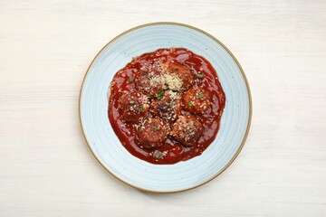 Delicious meatballs with tomato sauce, parmesan and herbs in on white wooden table, top view
