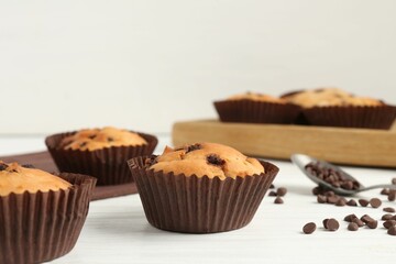 Delicious muffin with chocolate chips on white wooden table, closeup