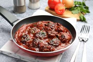 Delicious meatballs with tomato sauce and herbs in served on grey table