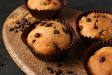Delicious muffin with chocolate chips on black table, closeup