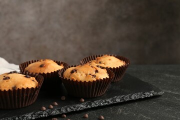 Delicious muffin with chocolate chips on black table, closeup