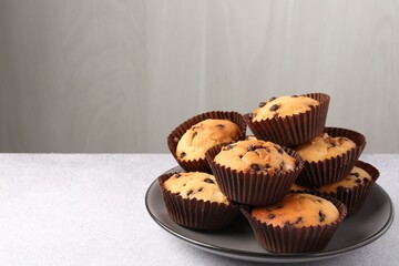 Delicious muffin with chocolate chips on light grey table, closeup. Space for text