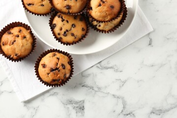 Delicious muffin with chocolate chips on white marble table, flat lay. Space for text