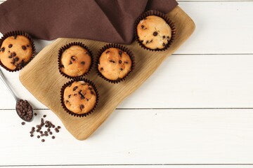 Delicious muffin with chocolate chips on white wooden table, flat lay. Space for text