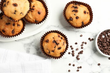 Delicious muffin with chocolate chips on white marble table, flat lay