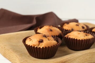 Delicious muffin with chocolate chips on table, closeup