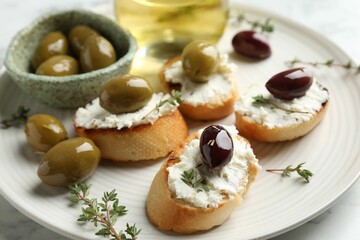 Delicious sandwiches with cream cheese and marinated olives on light table