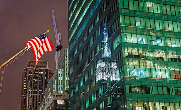 Night view of American flag reflecting on a building in New York City