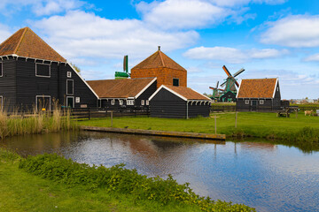Casas rurales y molinos de viento en Zaanse Schans, Países Bajos, junto a un canal y praderas verdes.