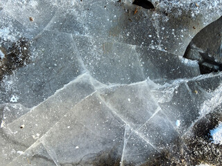 Ice with cracks. Danger on the ice in winter. Cracks in the ice on the lake. Texture, background with ice. Winter fishing on a frozen lake and river. Danger to life