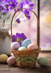 Easter eggs in a basket and purple daisies with colorful spring background