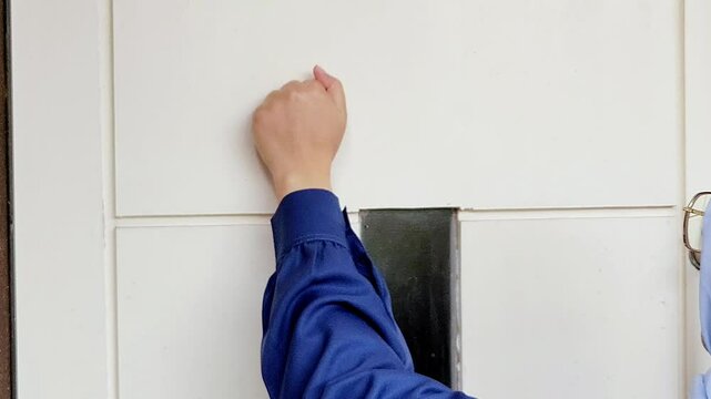 A young woman is knocking on the door of the house