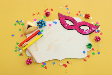 Purim celebration concept (jewish carnival holiday) over yellow background