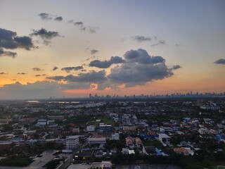 Aerial view of a bustling city at sunset with fluffy clouds