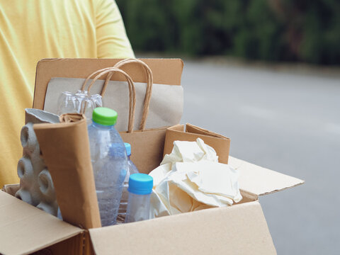 Young man hand holding box of garbage for recycling. Reuse reduce recycle concept.