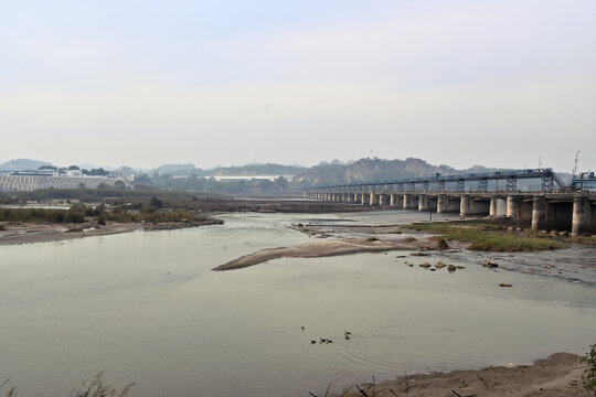 Concrete dam structure with multiple arches spans a wide river.