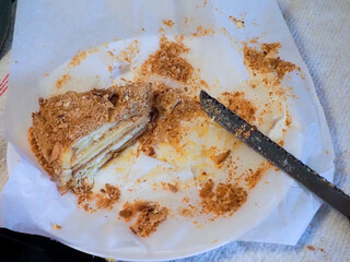 Partially Eaten Layered Cake with Crumbs and Knife on Parchment Paper
