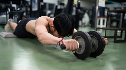 Asia Man training with bare torso abs wheel	