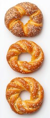 Three freshly baked, golden-brown pretzels arranged in a row, topped with sesame seeds, showcasing their twisted shape and inviting texture.