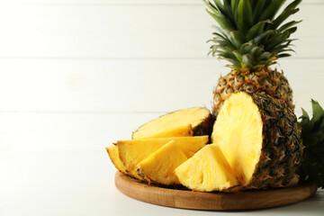 Whole and sliced fresh ripe pineapples on white table, space for text