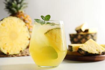 Tasty pineapple cocktail with mint in glass on light table, closeup