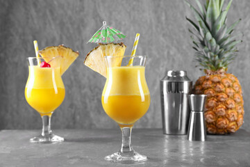Tasty pineapple cocktail in glasses served on grey table