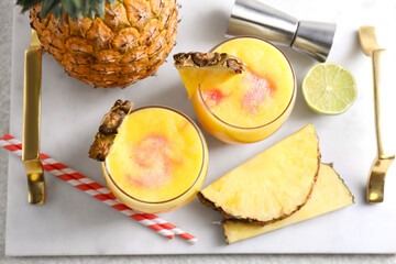 Tasty pineapple cocktail in glasses served on white table, flat lay