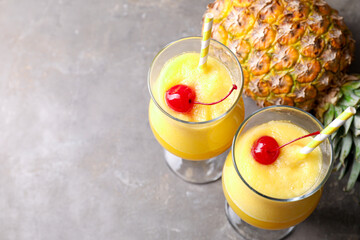 Tasty pineapple cocktail in glasses served on grey table, above view. Space for text