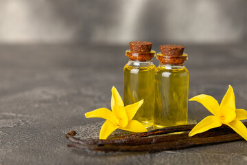 Bottle of vanilla essential oil with vanilla flower on textured background. aromatic vanilla beans....