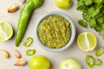 Delicious salsa sauce in bowl and ingredients on light textured table, flat lay
