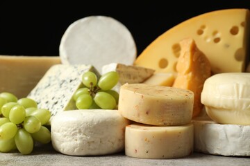 Different types of cheese and grapes on grey table, closeup