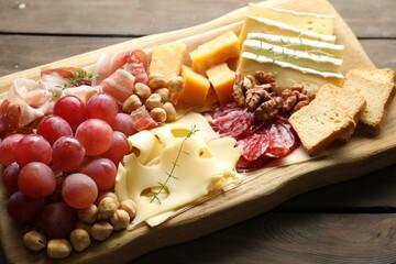 Different types of cut cheese and other snacks on wooden table, closeup