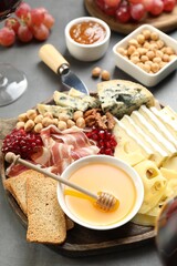 Different types of cut cheese and other snacks on gray table, closeup