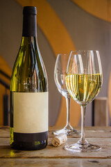 Manchester, United Kingdom, 2016: Elegant White Wine Bottle and Glasses on Rustic Wooden Table