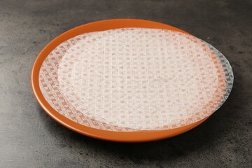 Edible rice paper sheets on grey textured table, closeup