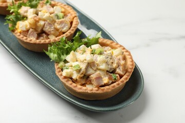 Tartlets with delicious filling on white marble table, closeup