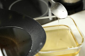 Pouring used cooking oil at white countertop, closeup