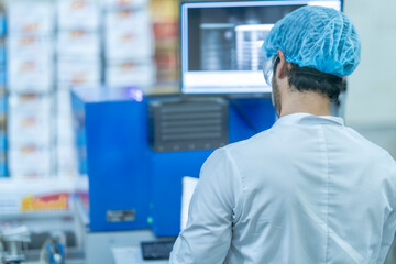A factory worker inspects product packaging with a computerized scanning system. This image highlights industrial automation, food safety, quality assurance, and manufacturing standards.