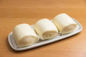 Plate of steamed buns on wooden table