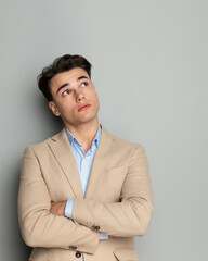 pensive young business student crossing arms and looking up side