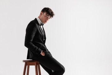 side view of handsome groom sitting and leaning forward