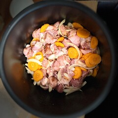 black pressure cooker inside with salt, spices, pork meat, onion and carrot. cooking at home. kitchen. dinner cooking process