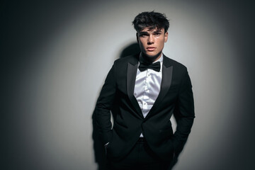 attractive young man in black tuxedo holding pockets