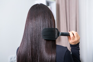Fototapeta premium woman combs her beautiful brunette hair at the beauty salon. Healthy hair