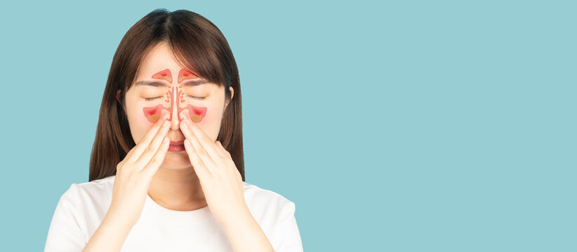 Asian woman suffering from sinusitis with nasal congestion of mucus or pus over blue background. Causes of rhinosinusitis include bacterial infections, viral infections and allergies.
